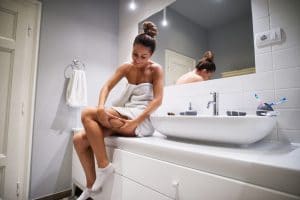 žena sedící na umyvadle v koupelně, kontroluje svá stehna